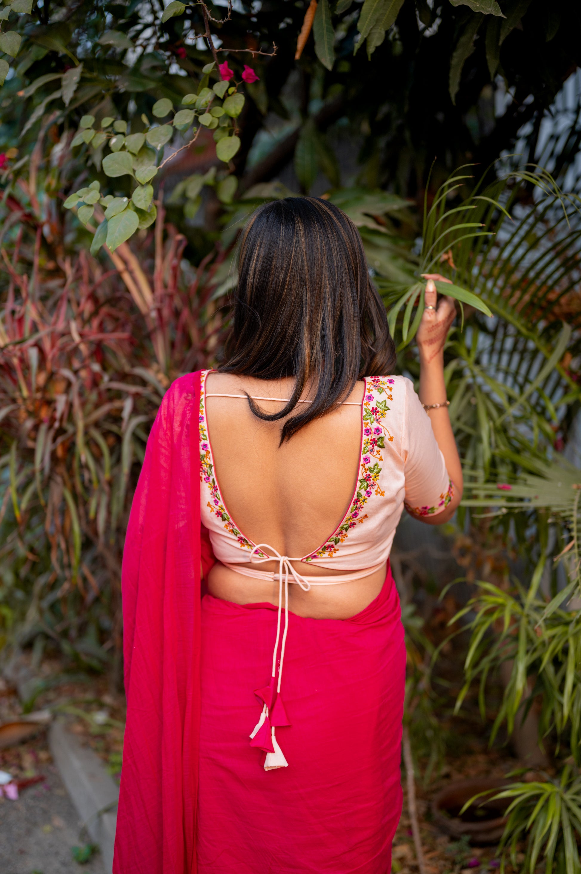 A peach cotton-linen blouse with multicolor floral embroidery, featuring a deep V neckline and back dori detailing to enhance your cotton saree looks.