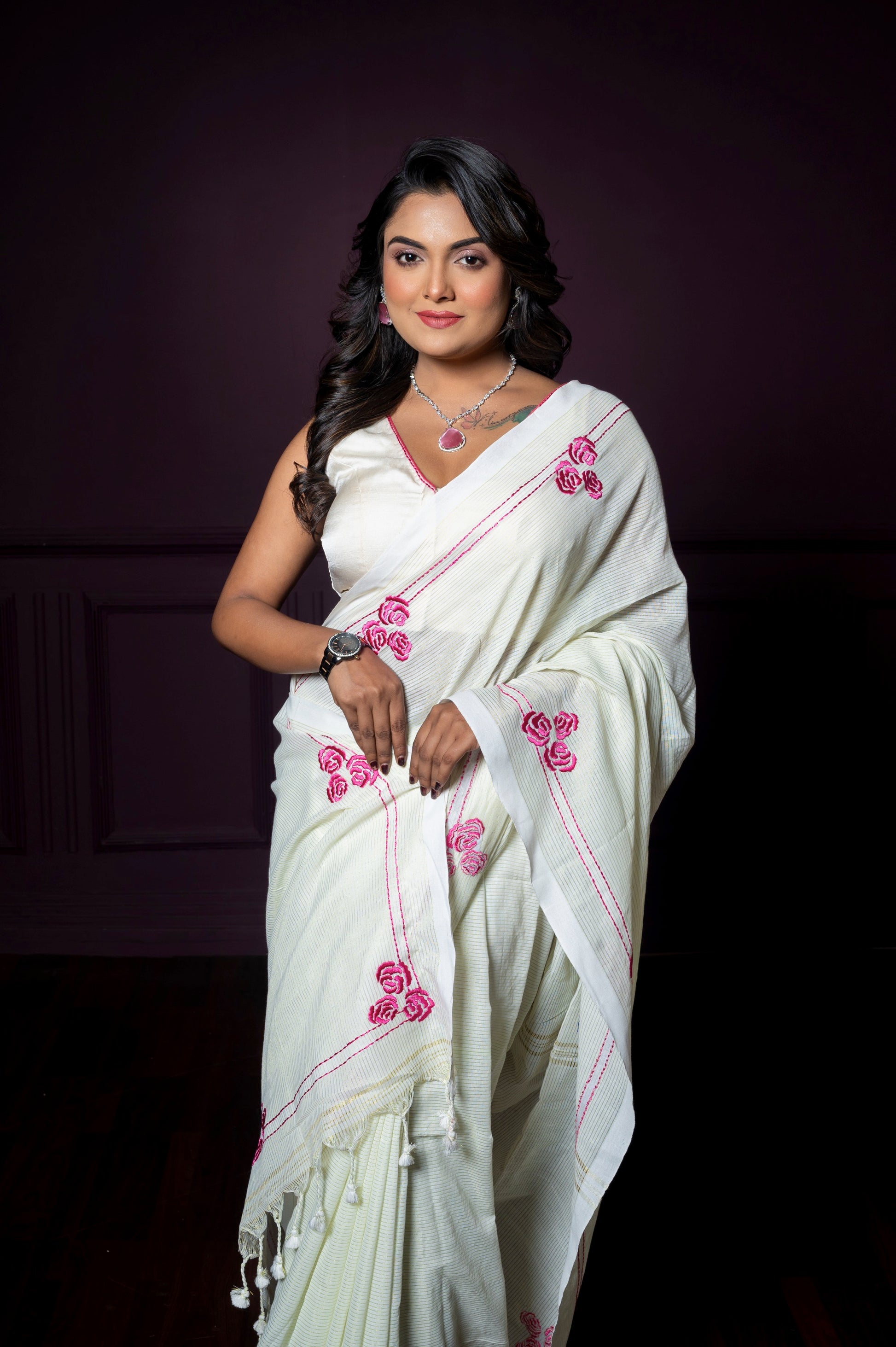 Woman in an off-white floral embroidered blouse paired with a matching saree, posing gracefully against a dark background.