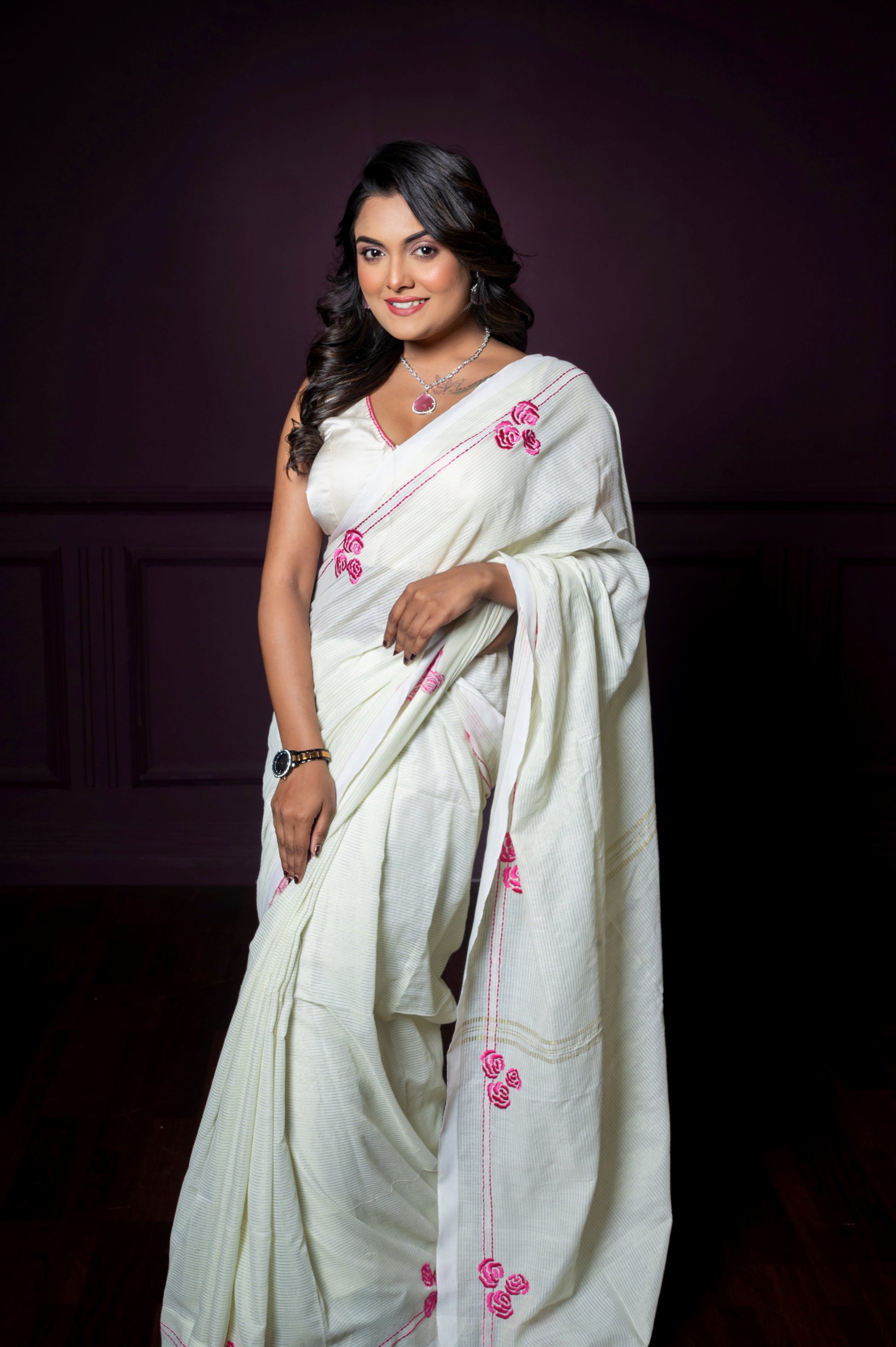 Front view of a sleeveless off-white blouse with pink floral embroidery, styled with an elegant white saree.