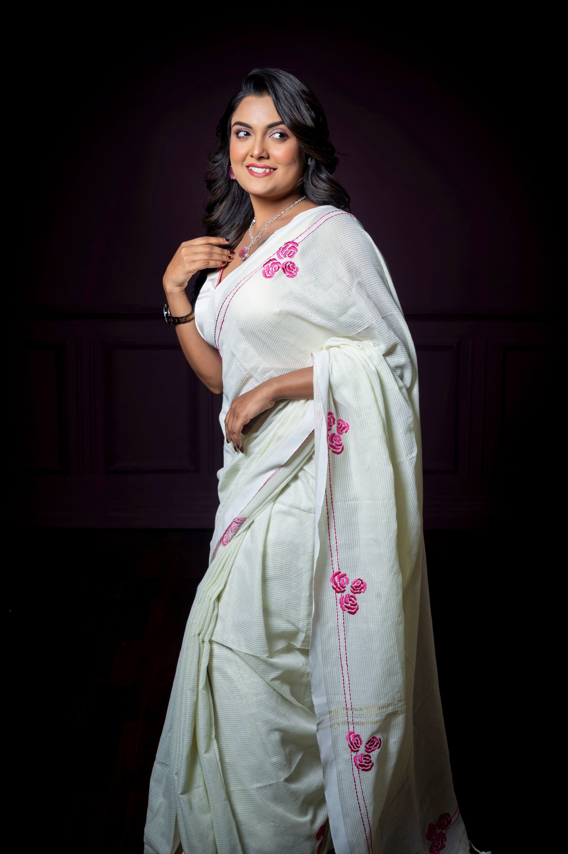Side pose of a woman in a semi-silk embroidered blouse with floral details, styled with a light saree.