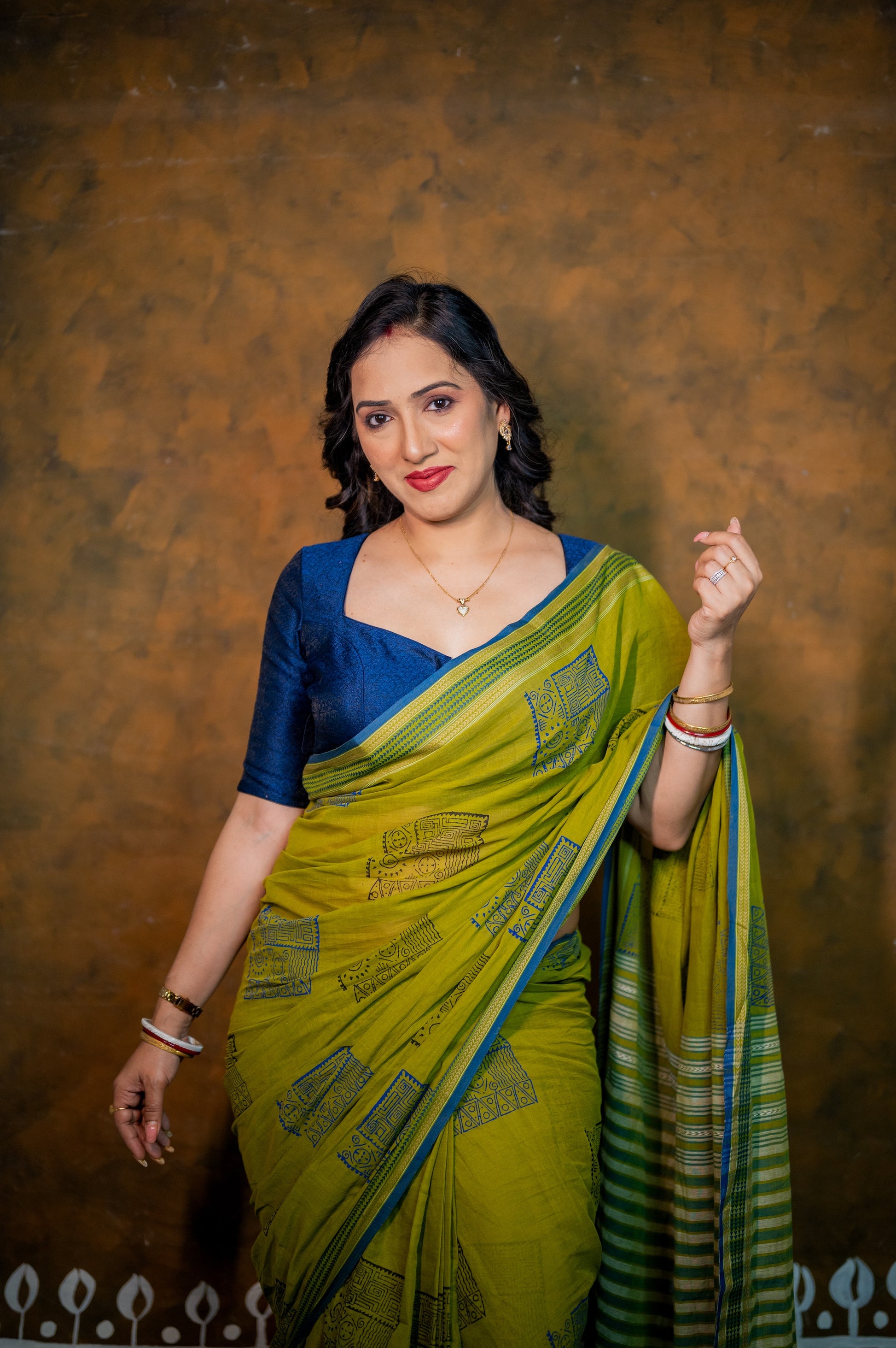 Elegant pose showcasing the deep neckline of the blue jamebar blouse and bright green saree.