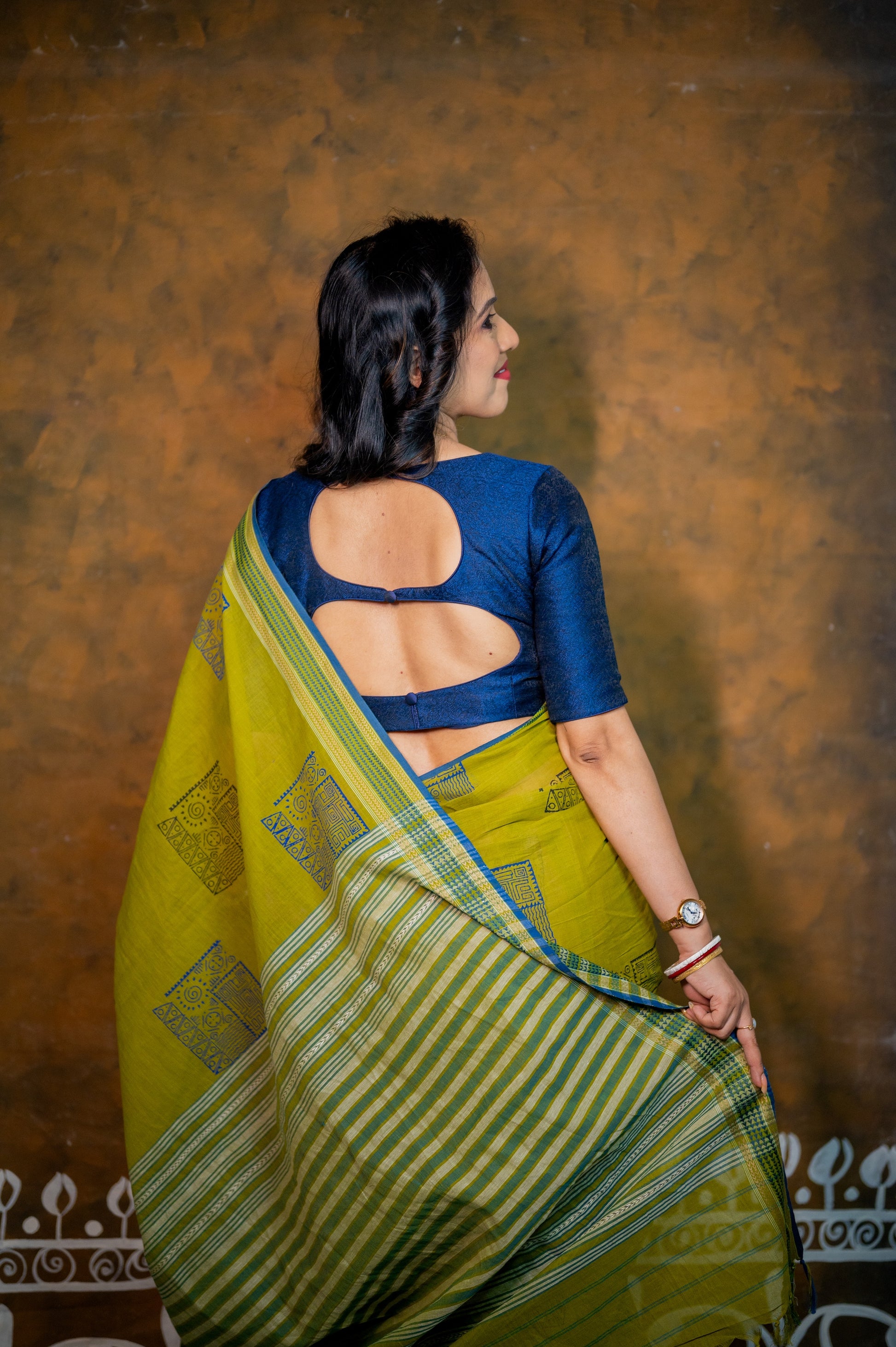 Back view of the blouse revealing the stylish designer back cut, complemented by a traditional green saree.