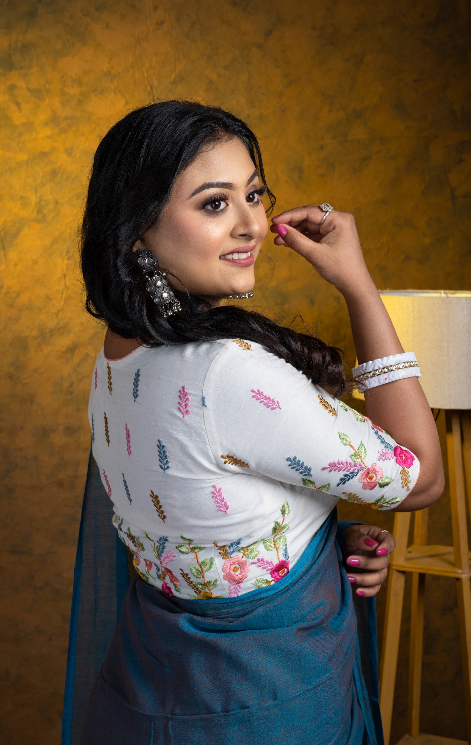 Back view of the Mono Maloti blouse showcasing vibrant pastel embroidery across the shoulder and back panel on crisp white cotton-linen.