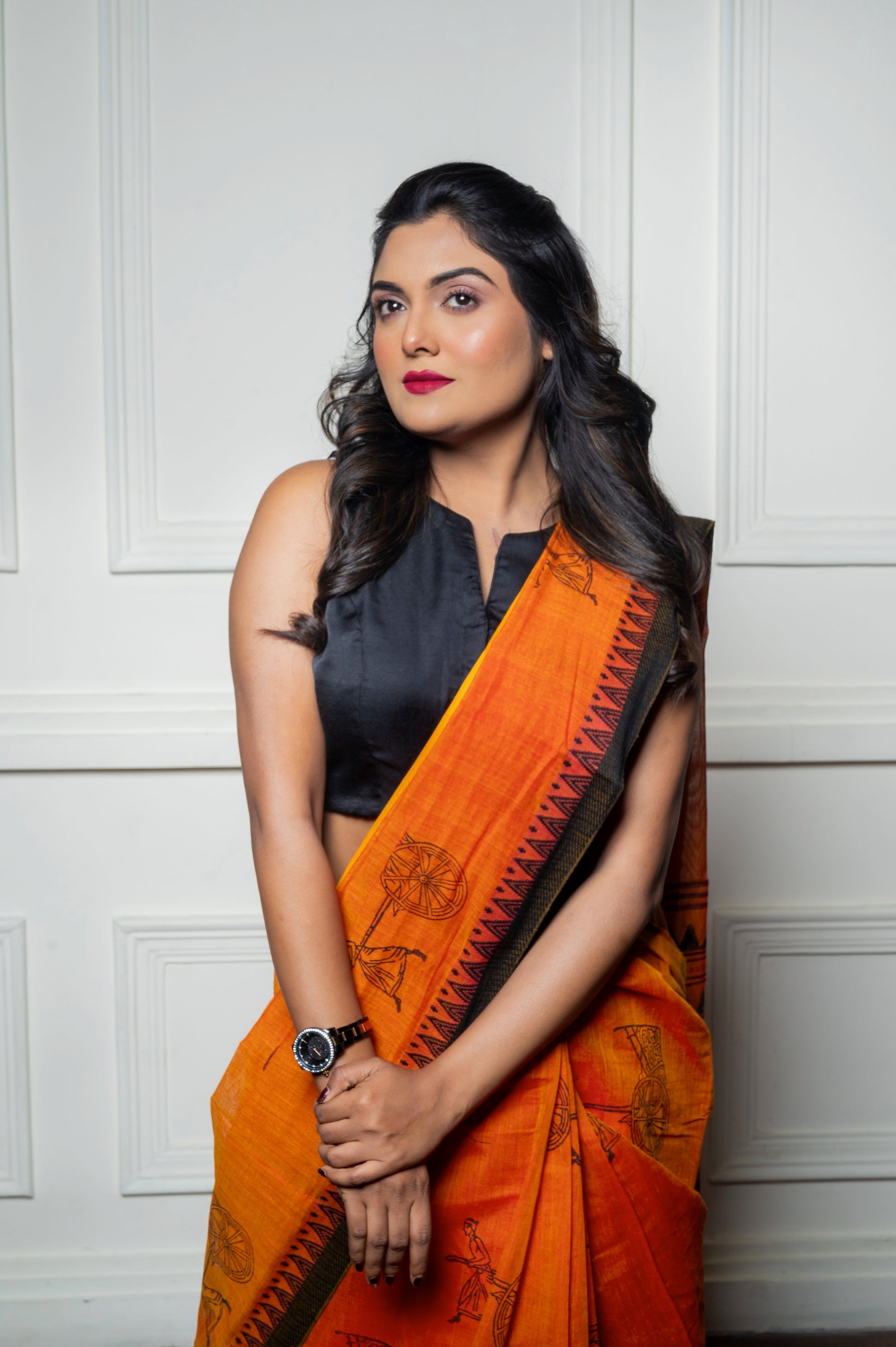 Front view of the black sleeveless blouse paired with an orange saree, showing the structured fit and sleek neckline.