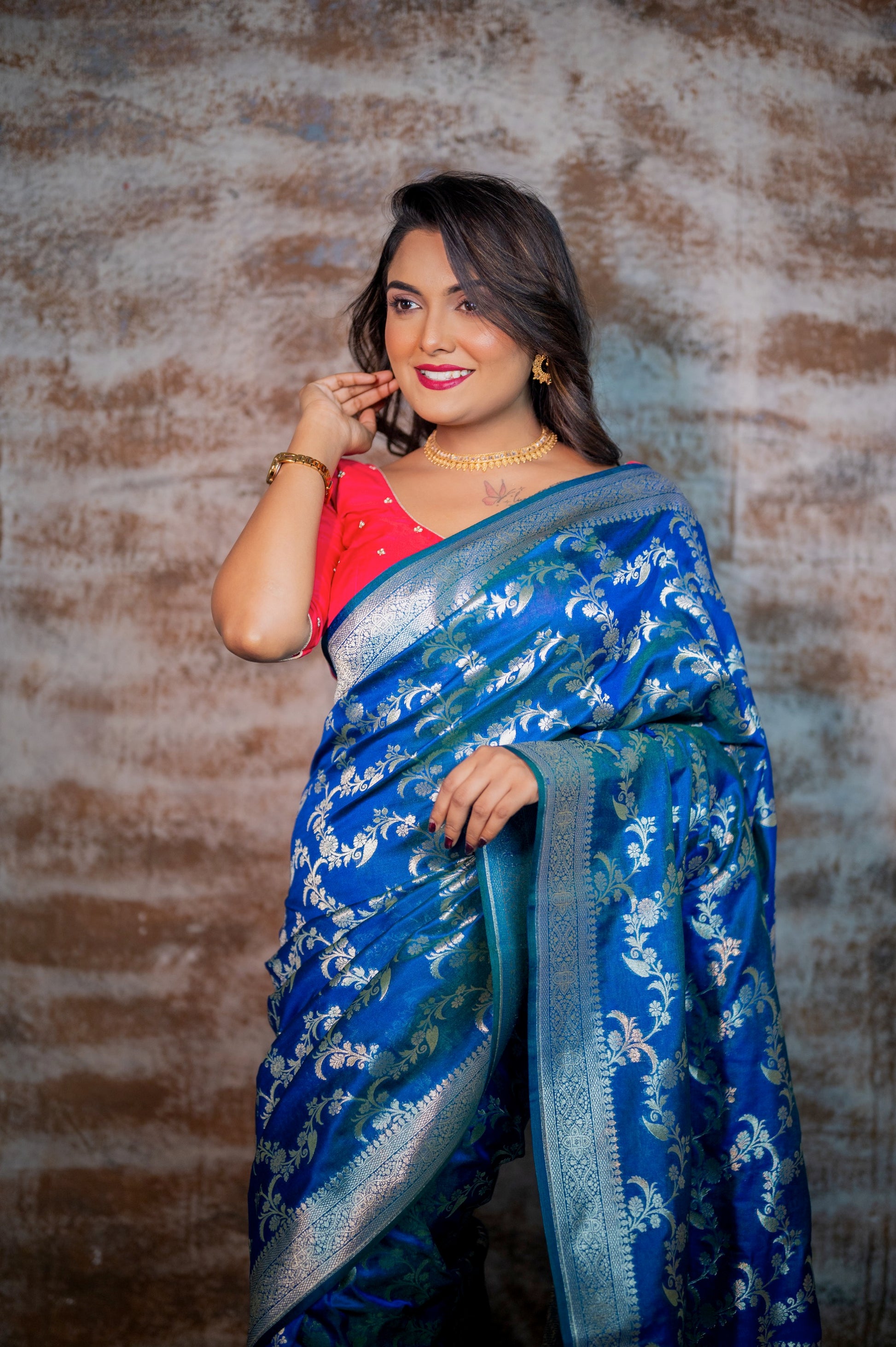 Woman in rani pink blouse with zardozi chita work paired with a royal blue banarasi saree, posing gracefully