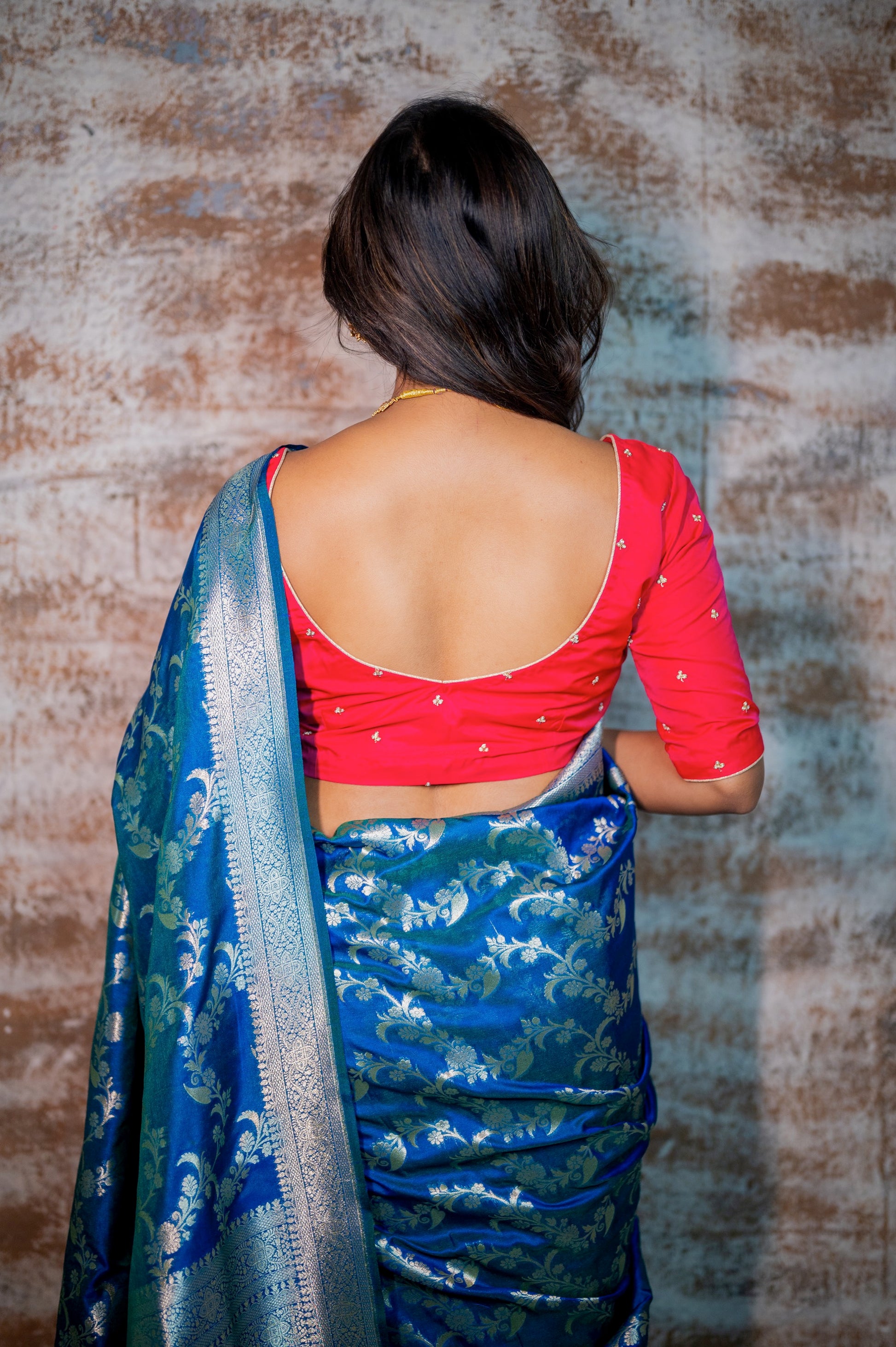 Close-up of elegant deep scoop back of rani pink silk blouse with delicate embroidery and white piping