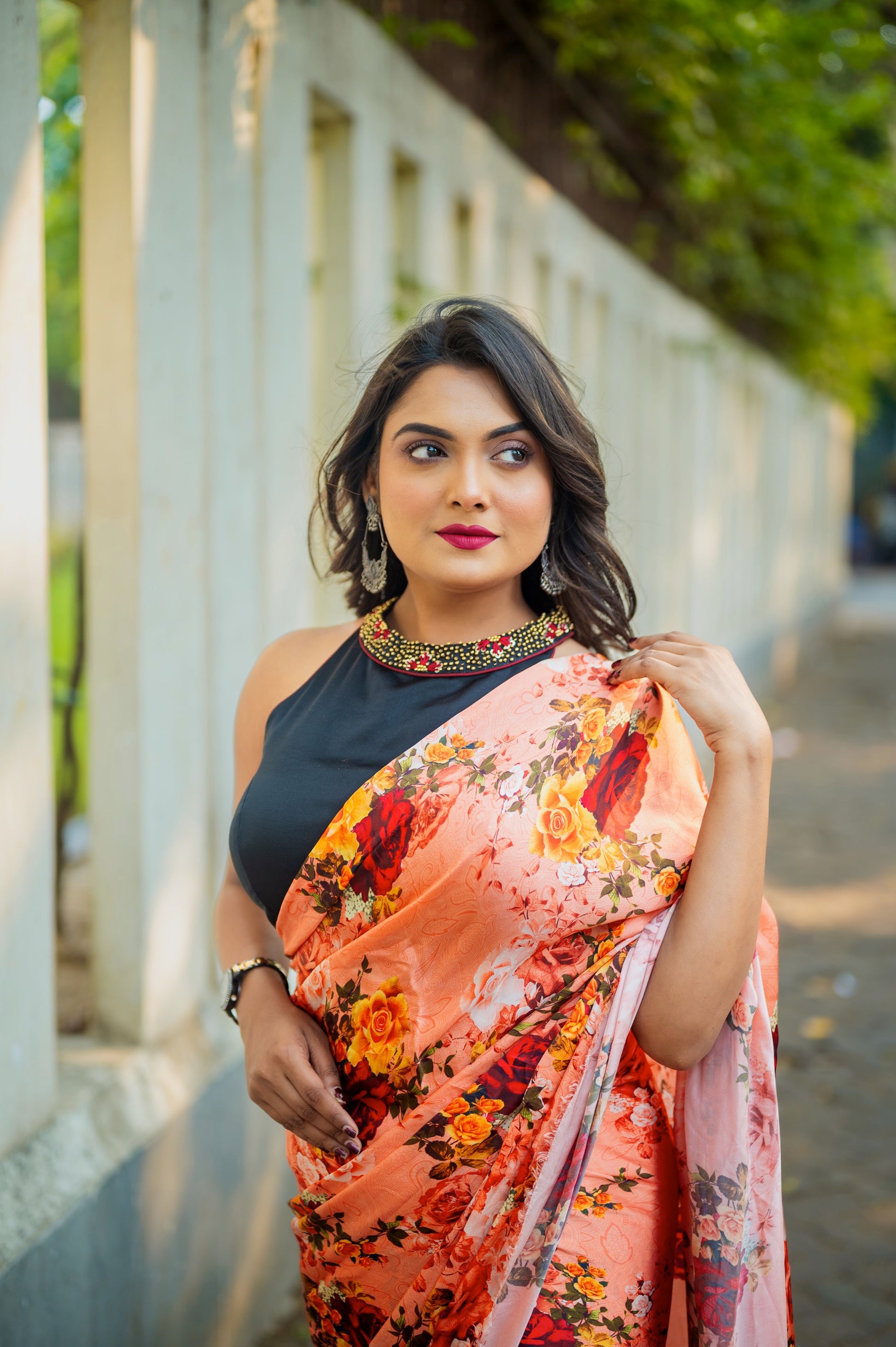 Close-up of a black halter-neck blouse with detailed hand zardozi embroidery on the collar, styled with a vibrant floral saree.