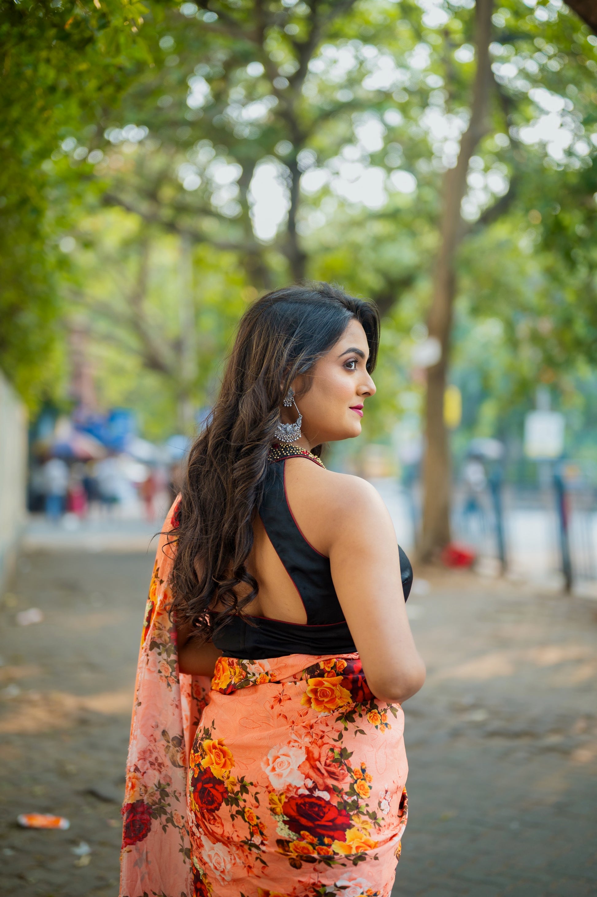 Back view of a black halter blouse with bold cutout design, highlighting the deep back and collar work paired with floral drape.