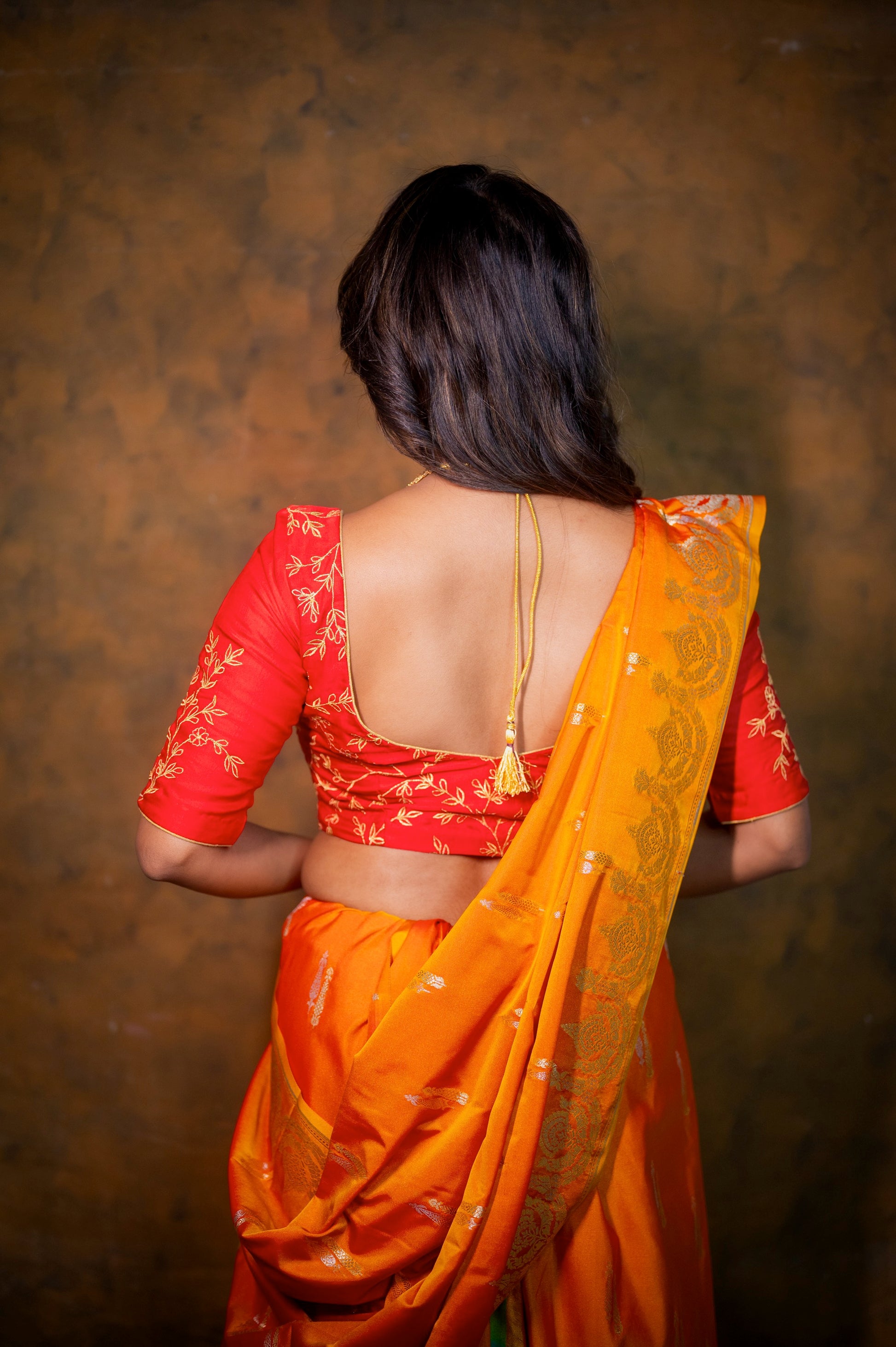Back view of the red blouse featuring a broad deep-cut back with a tie string and elbow-length sleeves.
