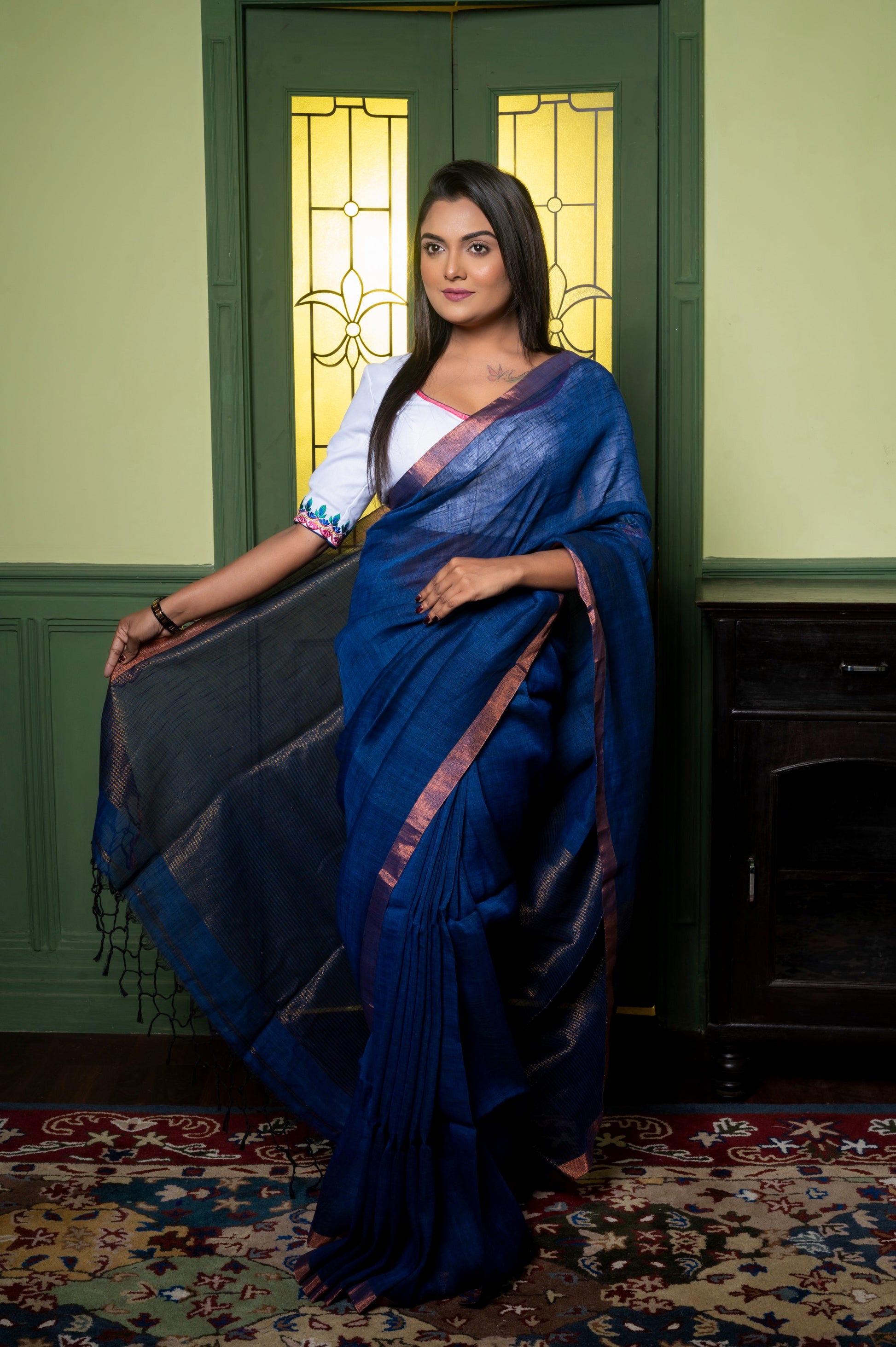 Front view of off-white cotton-linen blouse with pink piping and multicolor sleeve embroidery, styled with a deep blue saree.