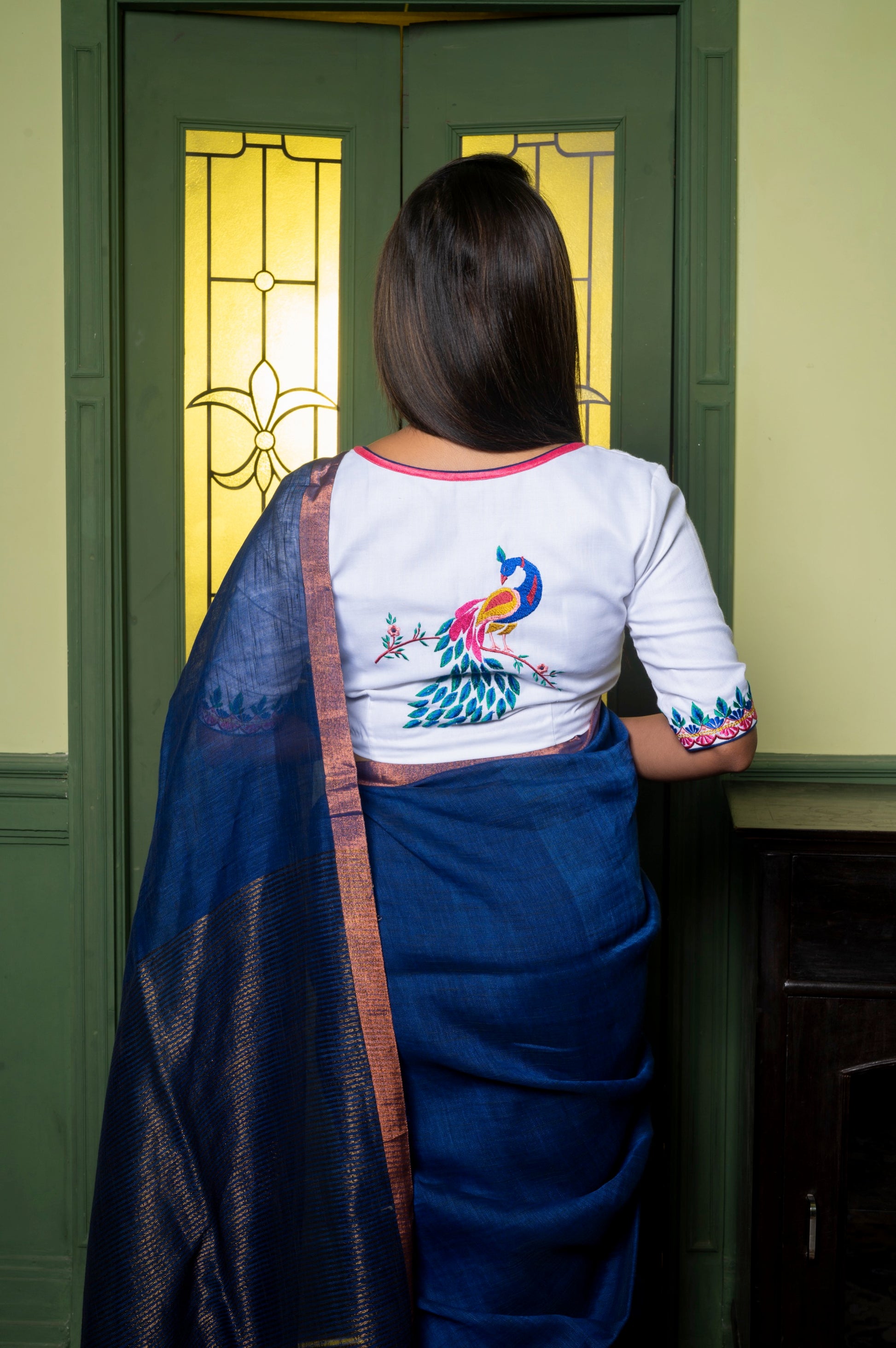 Back view of the Mann Mayuri blouse showcasing vibrant multicolor peacock embroidery on an off-white cotton base.