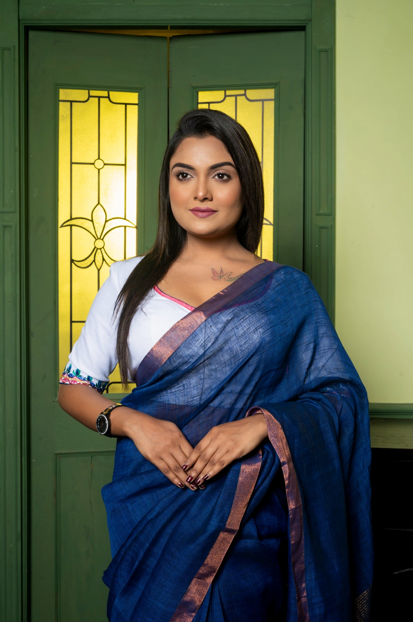 Close-up of wide V-neck cotton-linen blouse with multicolor embroidered sleeves, worn with a metallic-bordered blue saree.