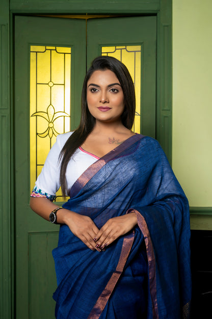 Close-up of wide V-neck cotton-linen blouse with multicolor embroidered sleeves, worn with a metallic-bordered blue saree.