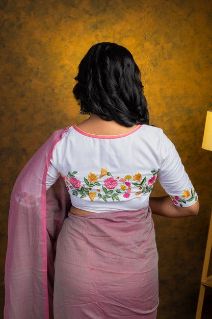Back view of a white cotton-linen blouse featuring colorful pastel silk thread embroidery of flowers and leaves, paired with a soft pink cotton saree for an everyday ethnic look