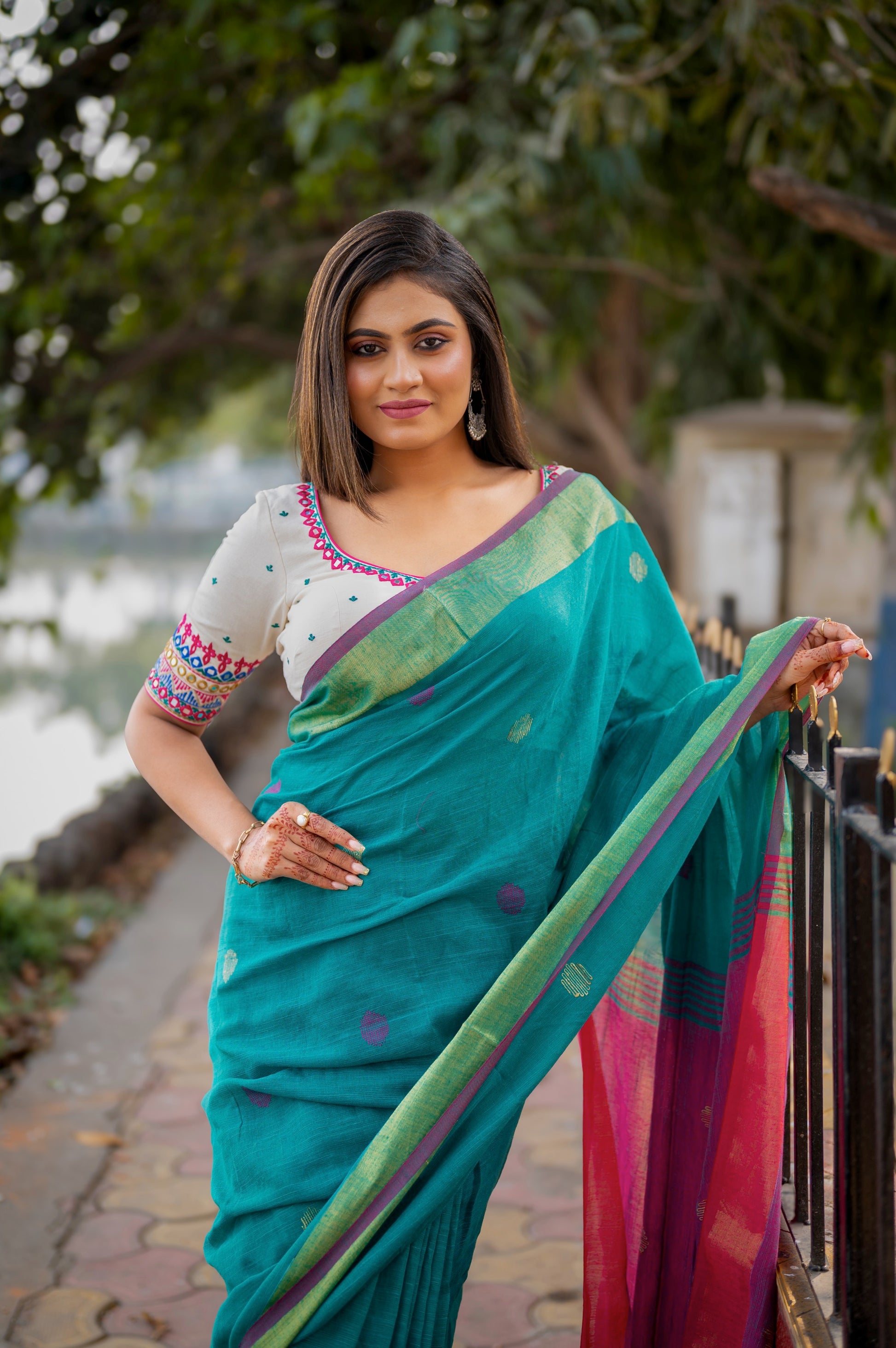 Front view of the embroidered cotton-linen blouse paired with a teal saree, highlighting the neckline and sleeve details.